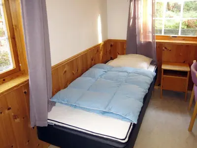 a small bed in a room with a window at Holiday Home Solsvika by Interhome in Leirvik