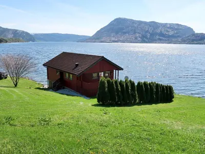 a small red house on the shore of a lake at Holiday Home Nanna by Interhome in Hyllestad
