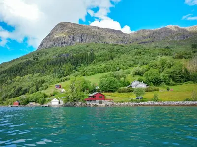 a village on the shore of a lake with mountains in the background at Holiday Home Idun by Interhome in Hyllestad