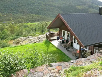 a house with a deck with a view of a mountain at Holiday Home Peer Gynt by Interhome in Sogndal