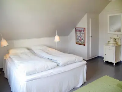 a white bedroom with a white bed and a green rug at Holiday Home Strøneneset by Interhome in Hagavik