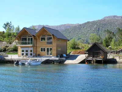 a house on a dock with a boat on the water at Apartment Huglavika by Interhome in Nordhuglo