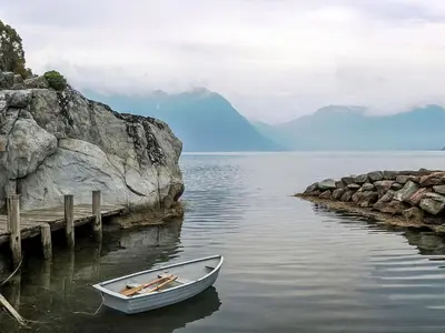 a small boat in the water next to a dock at Chalet Slåttenes by Interhome in Naustflot