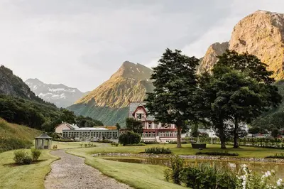 a house in a valley with mountains in the background at Hotel Union Øye in Øye