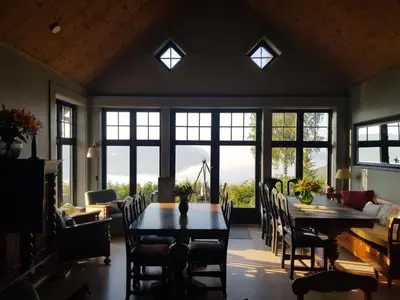 a dining room with a table and chairs and windows at Villa Fjara sleeps 22 in 6 bedrooms in Ulven