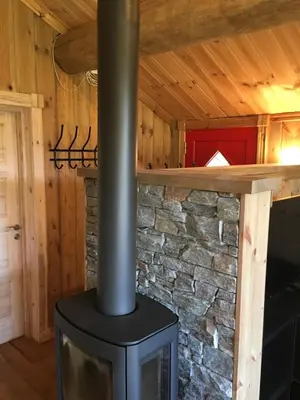 a wood stove in a room with a stone wall at Nilsrud 30 Feriehus in Åmotsdal