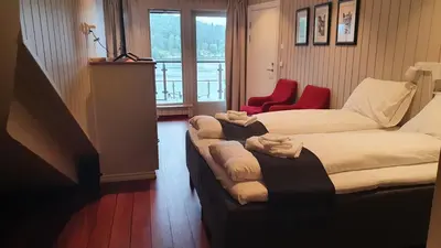 a living room with two beds and two red chairs at Villa Oleanna in Lysekloster