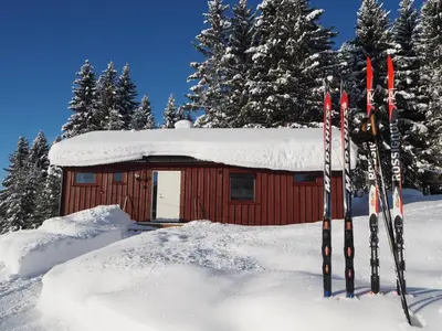 a cabin with skis in the snow in front of it at Cabin with great view close to town and ski area in Lillehammer
