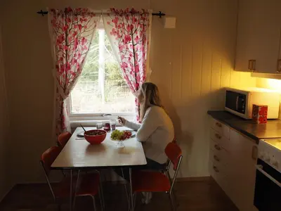 a woman sitting at a table in front of a window at Cabin with great view close to town and ski area in Lillehammer