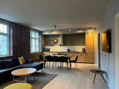 a living room with a couch and a table and a kitchen at Nygårdsgaten apartments in Bergen