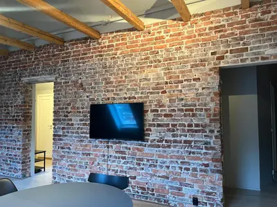 a tv on a brick wall with a table and chairs at Nygårdsgaten apartments in Bergen