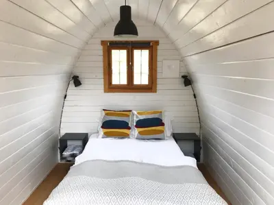 a bed in a small white room with a window at Valsøya in Valsøyfjord