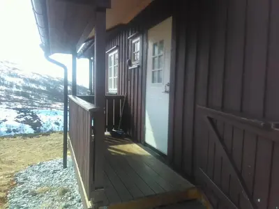 a wooden porch of a house with a white door at Bjørgo Gard - Stegastein in Aurland