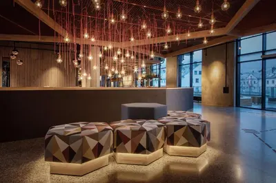 a lobby with a table and chairs and lights at Scandic Voss in Vossevangen
