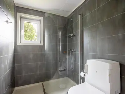 a bathroom with a shower and a toilet and a window at Holiday Home Rødehuset by Interhome in Gjelland