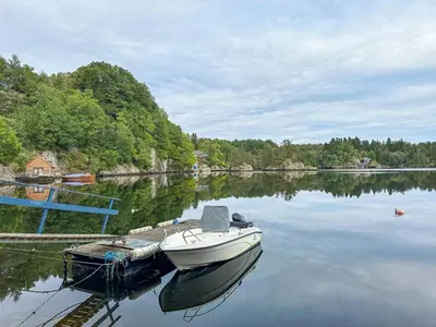 a boat is docked at a dock on a lake at Holiday Home Rødehuset by Interhome in Gjelland