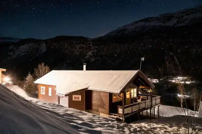 a small cabin in the snow at night at Cabin in Hodlekve with 5 bedrooms & hot tub. in Sogndal