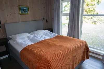 a bed with an orange blanket on it next to a window at Furetoppen Panorama in Stryn