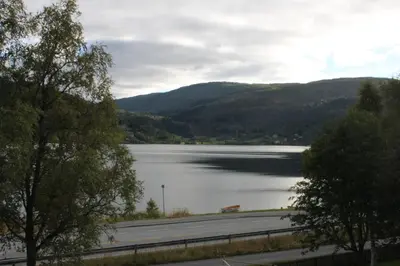 a large body of water with a road and mountains at Voss- Oppheim suite private cozy cabin in Vossestrand