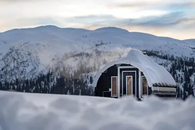 a building covered in snow with mountains in the background at Spåtind Fjellhotell in Nord Torpa