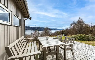a wooden table and chairs on a deck with a view of a lake at Awesome Home In Vatne With Wifi in Vatne