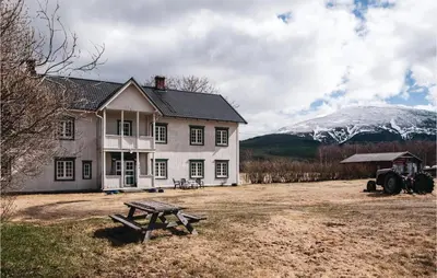 a house with a picnic table and a snow covered mountain at Beautiful Home In Tynset With Kitchen in Tynset