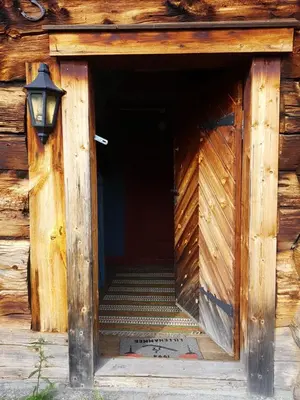 an open door of a wooden cabin with a light at Kvambekk Gard i Åmotsdal in Åmotsdal
