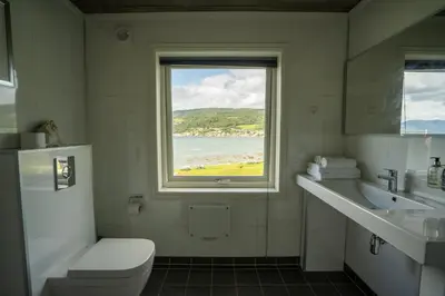 a bathroom with a toilet sink and a window at Eidsvåg Fjordhotell in Eidsvåg