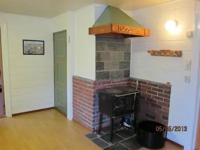 a living room with a brick fireplace and a green door at Presthus Gård in Ølve