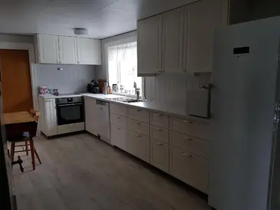 a kitchen with white cabinets and a refrigerator at Presthus Gård in Ølve