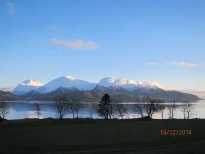 a view of a lake with mountains in the background at Presthus Gård in Ølve