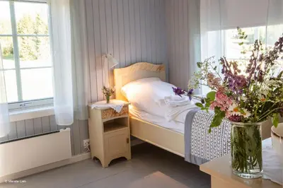 a small bedroom with a bed and a vase of flowers at Kirkvollen pilegrimsgård in Tydal