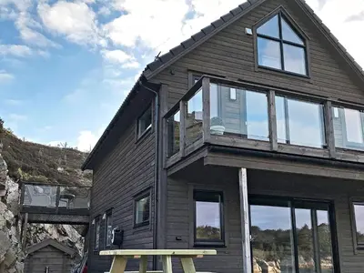 a wooden house with a bench in front of it at 8 person holiday home in Urangsvåg in Ervik