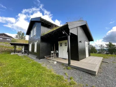 a small house with a porch and a wooden deck at Torshaug 4 bedroom cabin in Gol