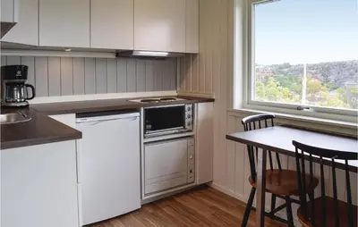 a kitchen with a stove and a table and a window at 2 Bedroom Cozy Home In Hauglandshella in Kolavåg