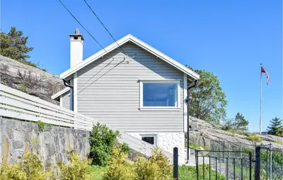 a white house with a stone wall at 2 Bedroom Cozy Home In Hauglandshella in Kolavåg