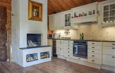 a kitchen with white cabinets and a fireplace at Cozy Home In Hemsedal With Kitchen in Hemsedal