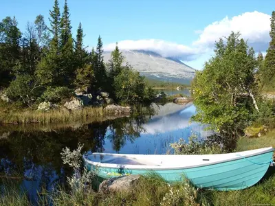 a blue boat sitting on the side of a river at Gaustatoppen Apartment in Rjukan