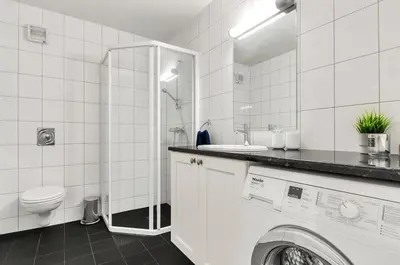 a white tiled bathroom with a washing machine in it at Gaustatoppen Apartment in Rjukan