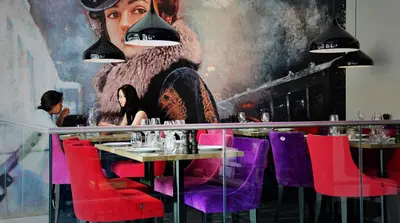 a restaurant with purple chairs and a large painting on the wall at Hotel No13 in Bergen