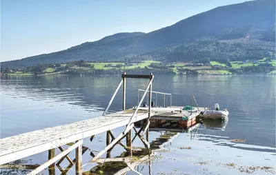 a dock on a lake with mountains in the background at 2 Bedroom Amazing Apartment In Vestnes in Vestnes