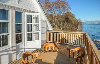 a wooden deck with a table and chairs on the water at 2 Bedroom Amazing Apartment In Vestnes in Vestnes