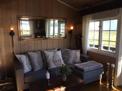 a living room with a couch and two windows at Kjøniksbu - 3 bedroom cabin in Ål
