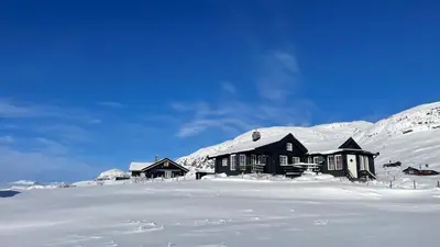 a house is covered in snow in front of a mountain at Veslehytta - cabin 1050 moh via amazing view and ambiance in Ål