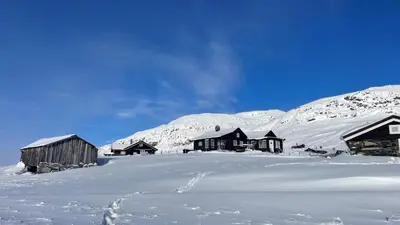 a group of buildings in the snow with mountains at Veslehytta - cabin 1050 moh via amazing view and ambiance in Ål