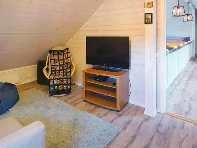 a living room with a television on a wooden stand at 8 person holiday home in Åram in Sandvik