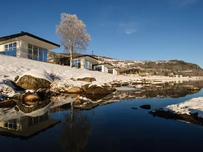 a house with snow on the ground next to a body of water at Topcamp Hallingdal - Ål in Ål