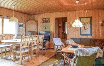 a living room with wooden walls and a table and chairs at Stunning Home In Sjusjøen With Kitchen in Sjusjøen