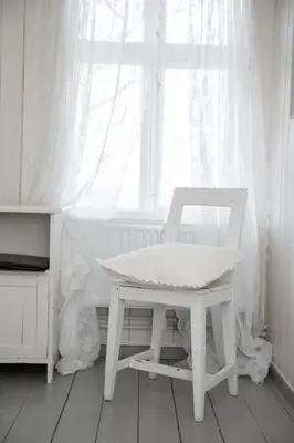 a white chair and a table in front of a window at Skjerjehamn in Ånneland
