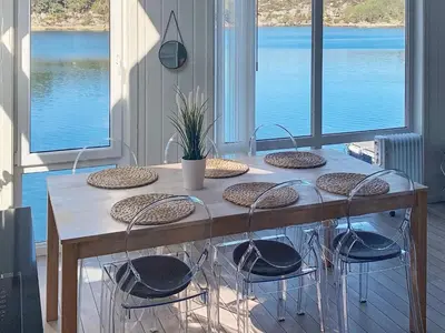 a wooden table with chairs and a large window at 6 person holiday home in Urangsvåg in Steinsbø